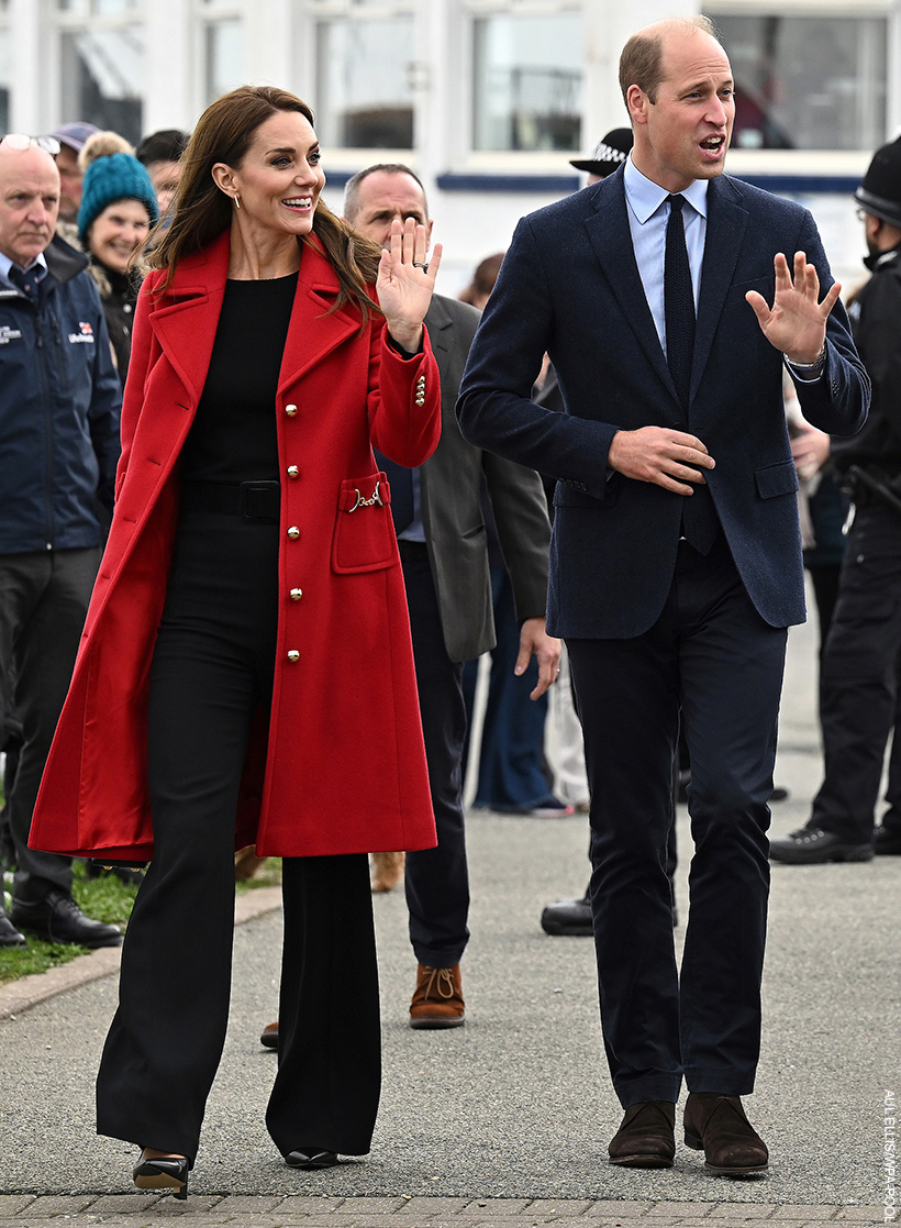 Prince William and Kate Midldeton visiting Wales. The pair are waving to crowds waiting. The Princess is wearing a bold red coat.